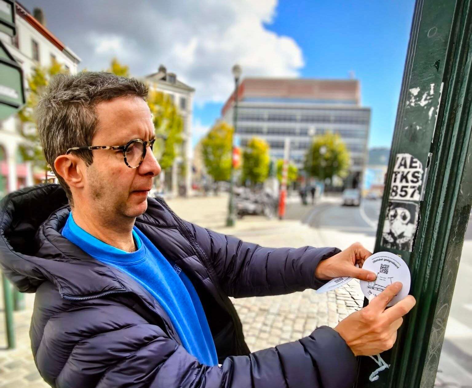 Nick kleeft sticker op paal