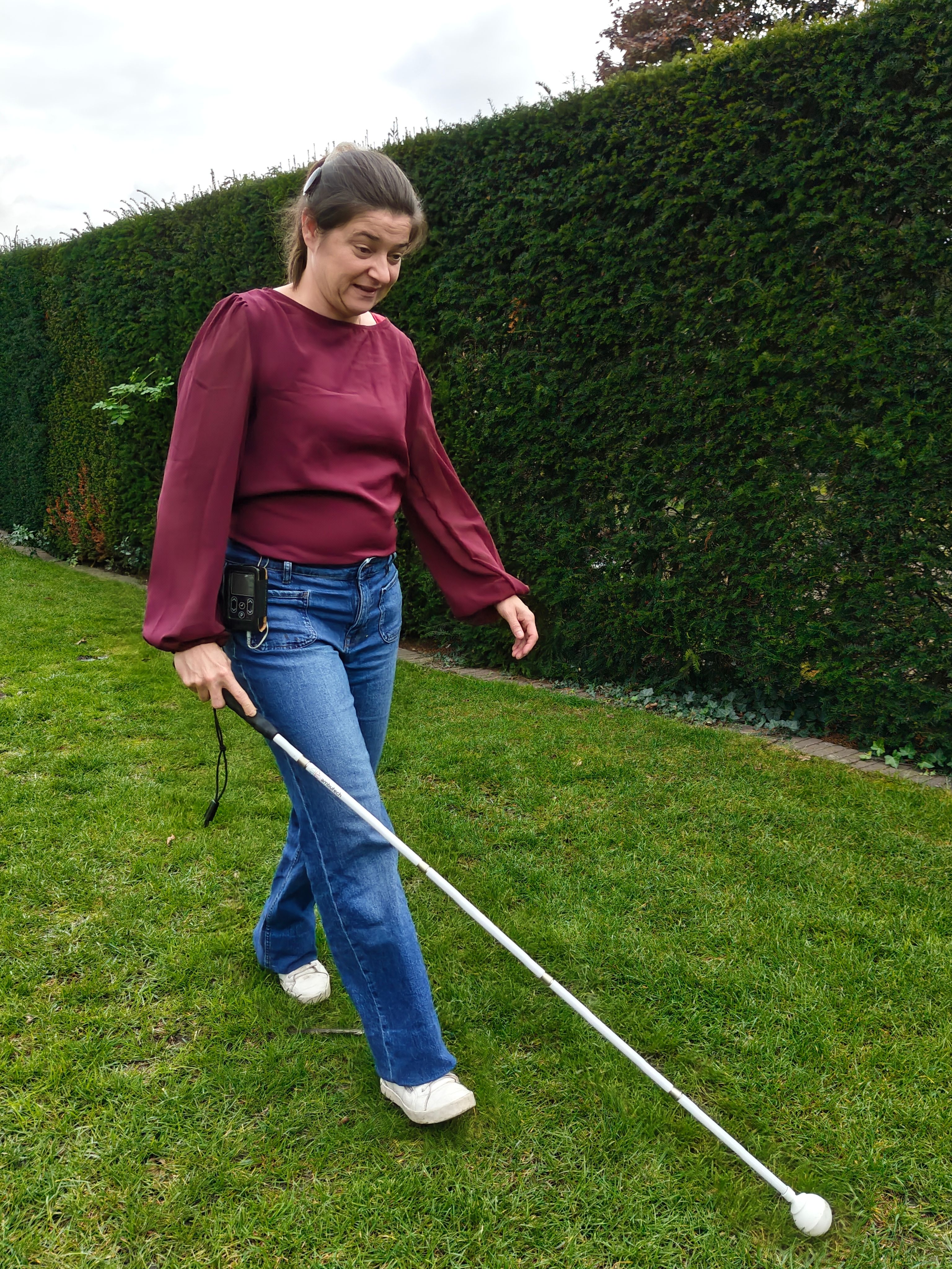 Tamara loopt met haar witte stok door de tuin