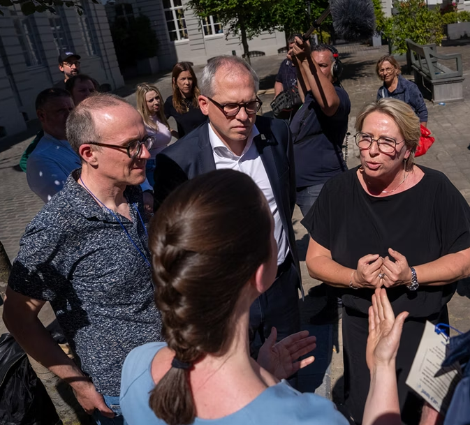 Op de afbeelding staan verschillende mensen die met elkaar aan het praten zijn, waaronder minister Gennez, minister Diependaele, Dave Ceule van Onafhankelijk Leven.